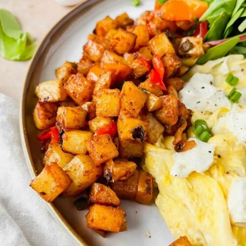 Copycat ihop breakfast potatoes plated beside scrambled eggs and spinach.