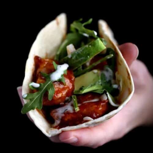 A hand holding Koreatown Tacos on a black background.