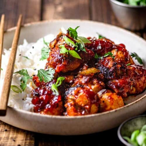 Air-Fried Korean Cauliflower served in a bowl over a bed or cooked rice and topped with green onion.