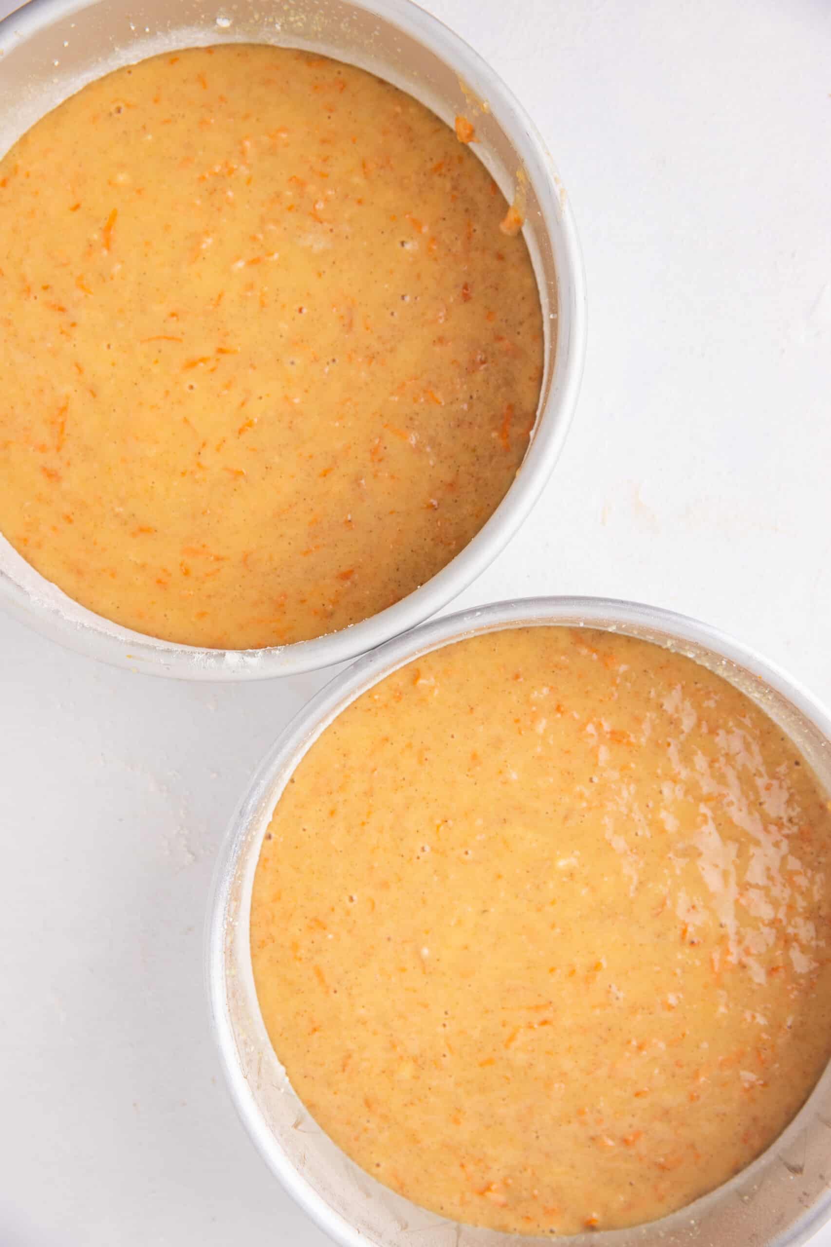 Two round cake pans with carrot cake batter.