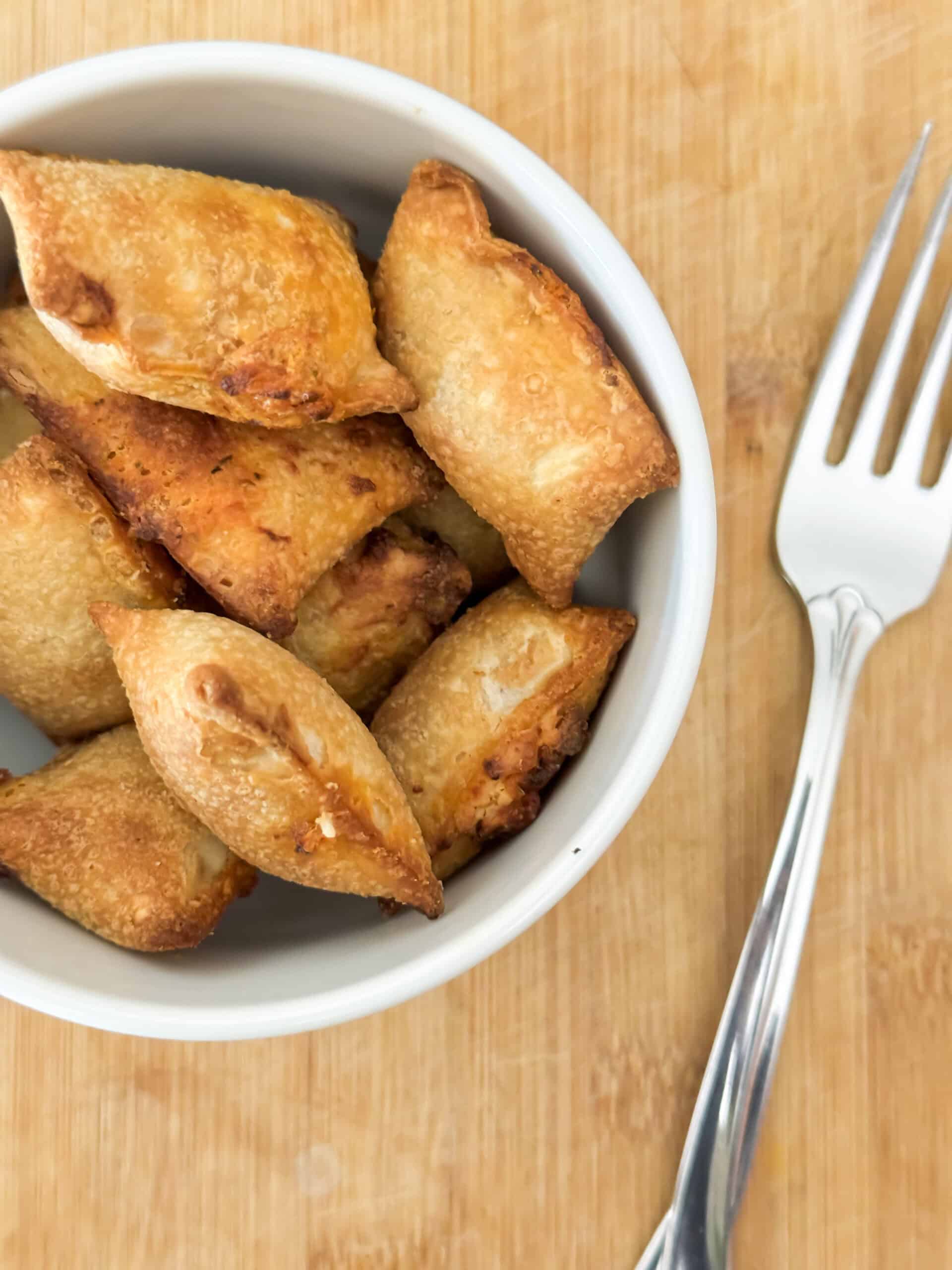 front view of pizza rolls on white plate with some cheese oozing out.