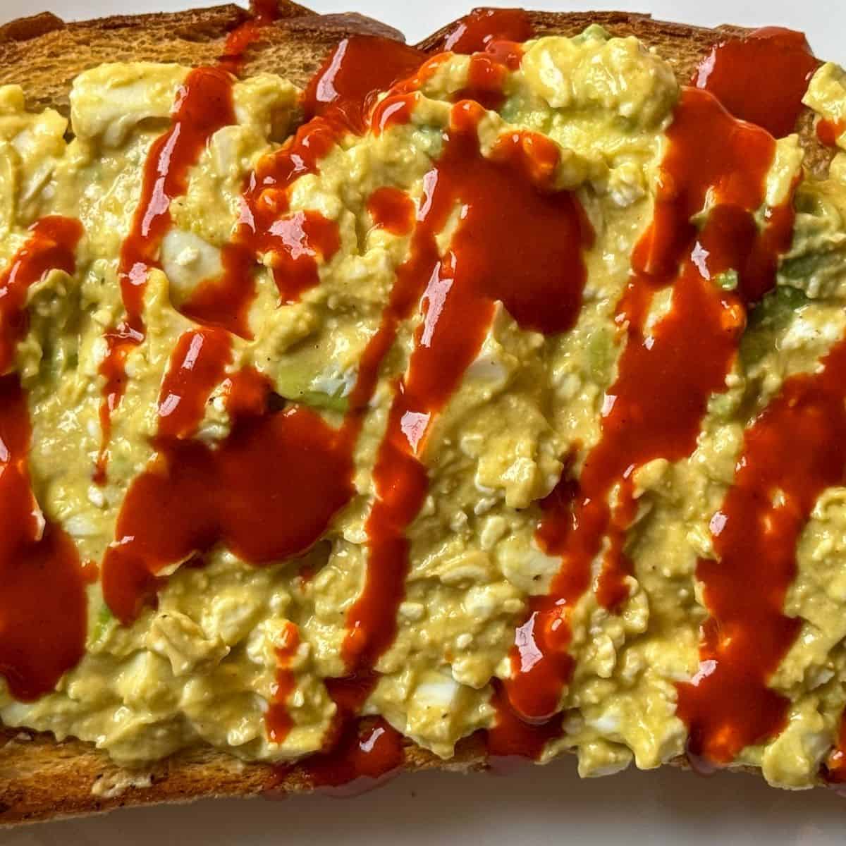 Single-Slice-Avocado-Cottage-Cheese-on Sourdough toast with hot sauce drizzle