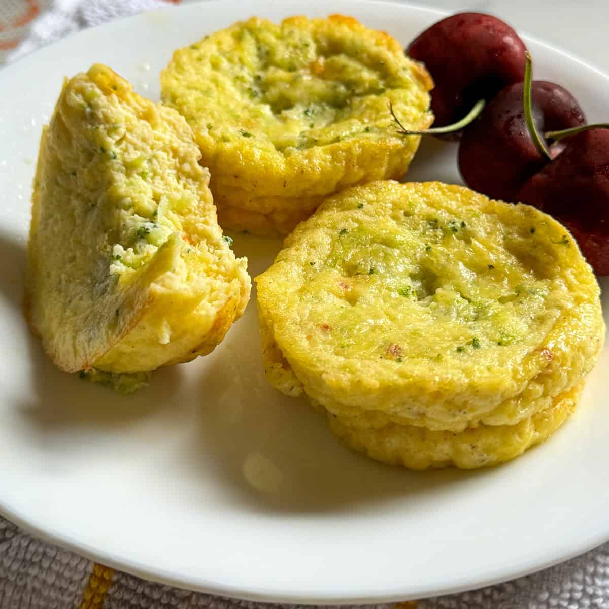 Plate of 3 cottage cheese egg bites served with 3 cherries - with lighting altered v2