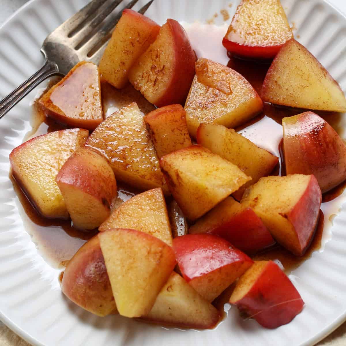 Cinnamon apples served on a plate with a fork on the side