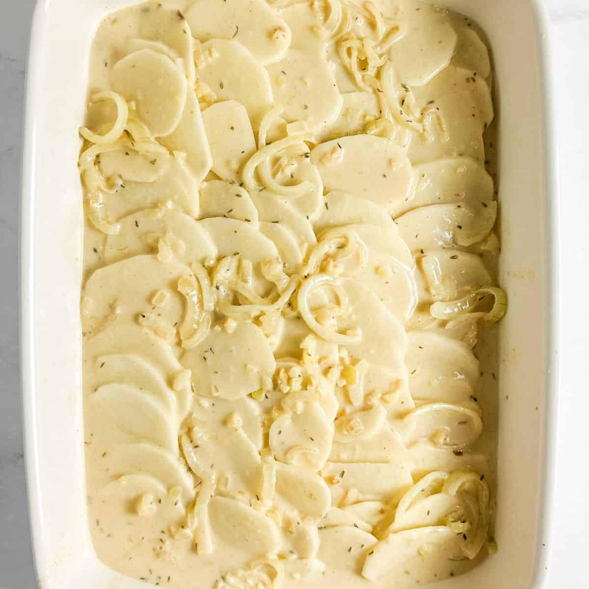 Arranged sliced potatoes in an even layer in the prepared baking dish. Step 4 of process