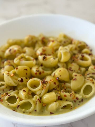 Pesto Cottage Cheese pasta sauce served on a white plate with crushed red chili flakes sprinkled on top