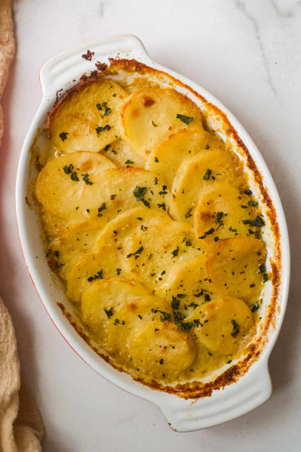 Baked Dairy Free Scalloped Potatoes fresh out of the oven in a baking dish on a white background